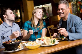 Young couple with older man eating Mexican and laughing